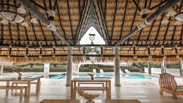 A covered outdoor area with a pool, wooden furniture, and a thatched roof structure. - Hacienda Oro Verde (San Jerónimo)