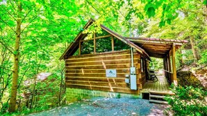 A wooden cabin with a sloped roof, a small porch, and a sign indicating it is a campground. - Hidden Treasure (Sevierville)