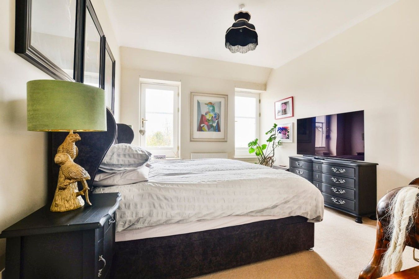 Um quarto com uma cama, penteadeira, televisão e abajur.