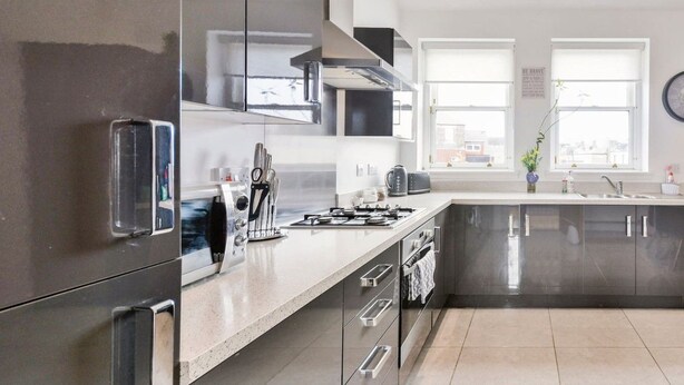 Una cocina moderna con electrodomésticos de acero inoxidable, una estufa a gas y una isla grande con un lavamanos.