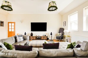 Una sala de estar con un sofá, un televisor de pantalla plana y una lámpara.