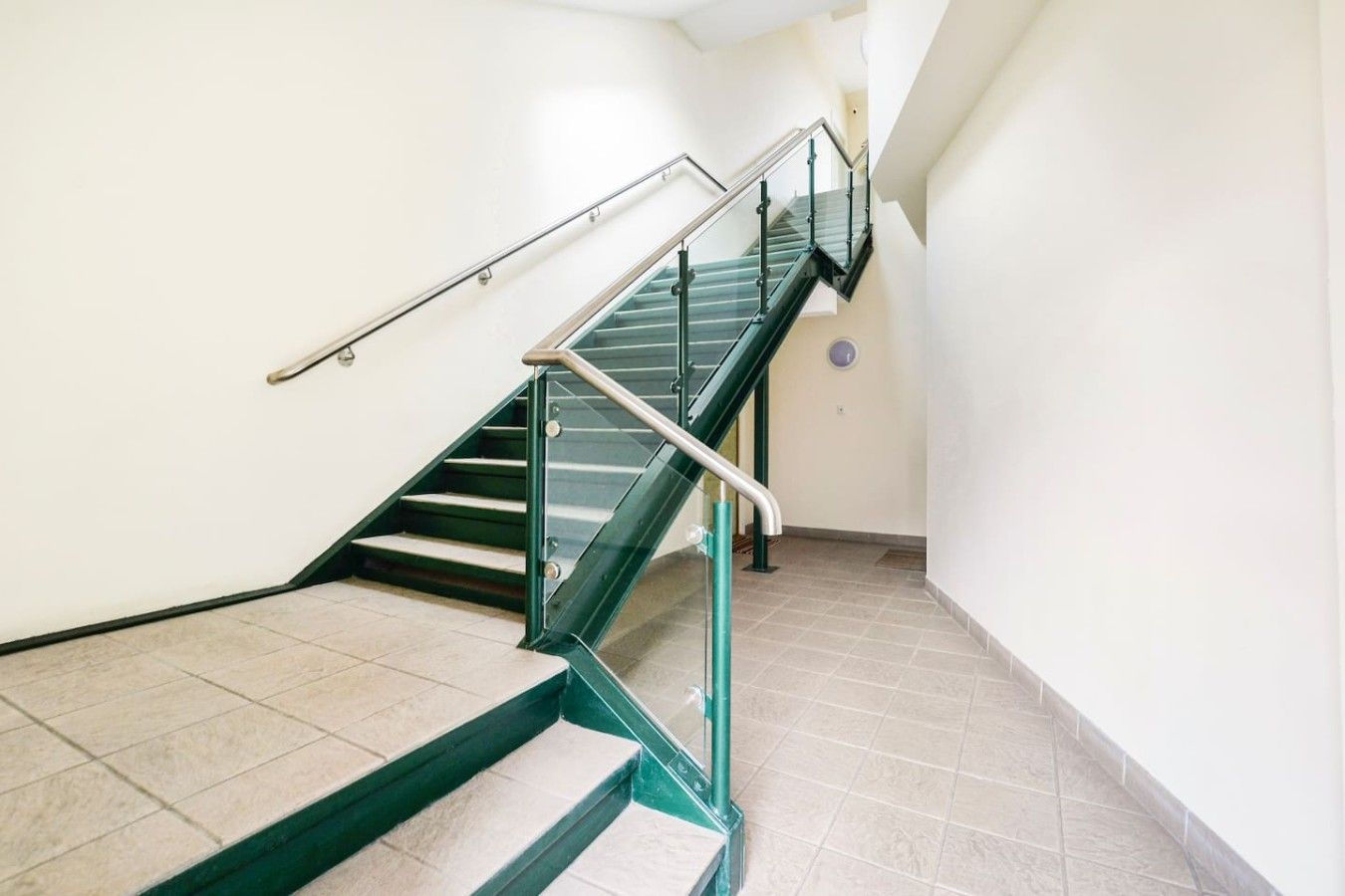 Eine Treppe mit Glas- und Metallgeländern, die zu einer oberen Etage führt.