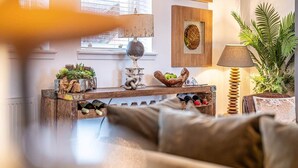 A cozy living room with a sofa, a wooden coffee table, a lamp, and a potted plant.