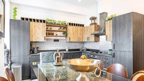 A modern kitchen with dark wood cabinets, a central island with a copper bowl, and a variety of decorative items.