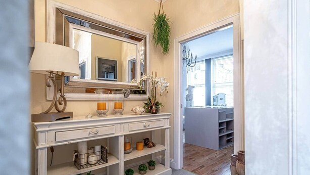 A bathroom with a vanity, mirror, shelves with candles, and a hanging plant.