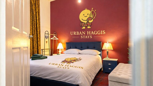 Une chambre d’hôtel comprenant un lit, des tables de chevet, une lampe, un porte-manteau mural et un mur orné d’une illustration et d’un texte.