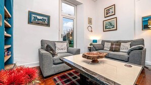 Un salon moderne avec deux canapés gris, une table basse en bois et un tapis à carreaux rouges et noirs.