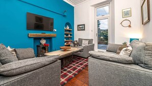 Un salon moderne avec un mur d’accent bleu, une cheminée, un téléviseur et une grande fenêtre offrant une belle vue.