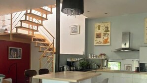 Une cuisine moderne dotée d’un îlot central, d’un escalier et d’un coin repas.