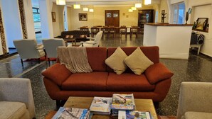 A cozy lobby with a red sofa, a coffee table with magazines, and a dining area in the background. - Bosque De Bohemia Delta Tigre (Partido de Tigre)