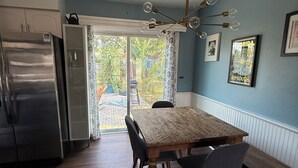 Una cucina con un tavolo e sedie in legno, un frigorifero in acciaio inossidabile e un lampadario.