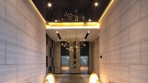 A modern hallway with a tiled floor, a central chandelier, and decorative lighting fixtures. - Sea View Room Luxury Amenities (Pattaya)