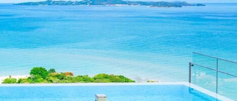 An infinity pool with a clear view of the ocean and distant land.