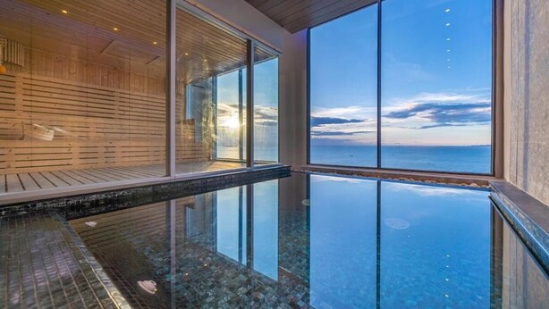A modern infinity pool with a clear view of the sea, wooden paneling, and large windows. - Sea View Room Luxury Amenities (Pattaya)