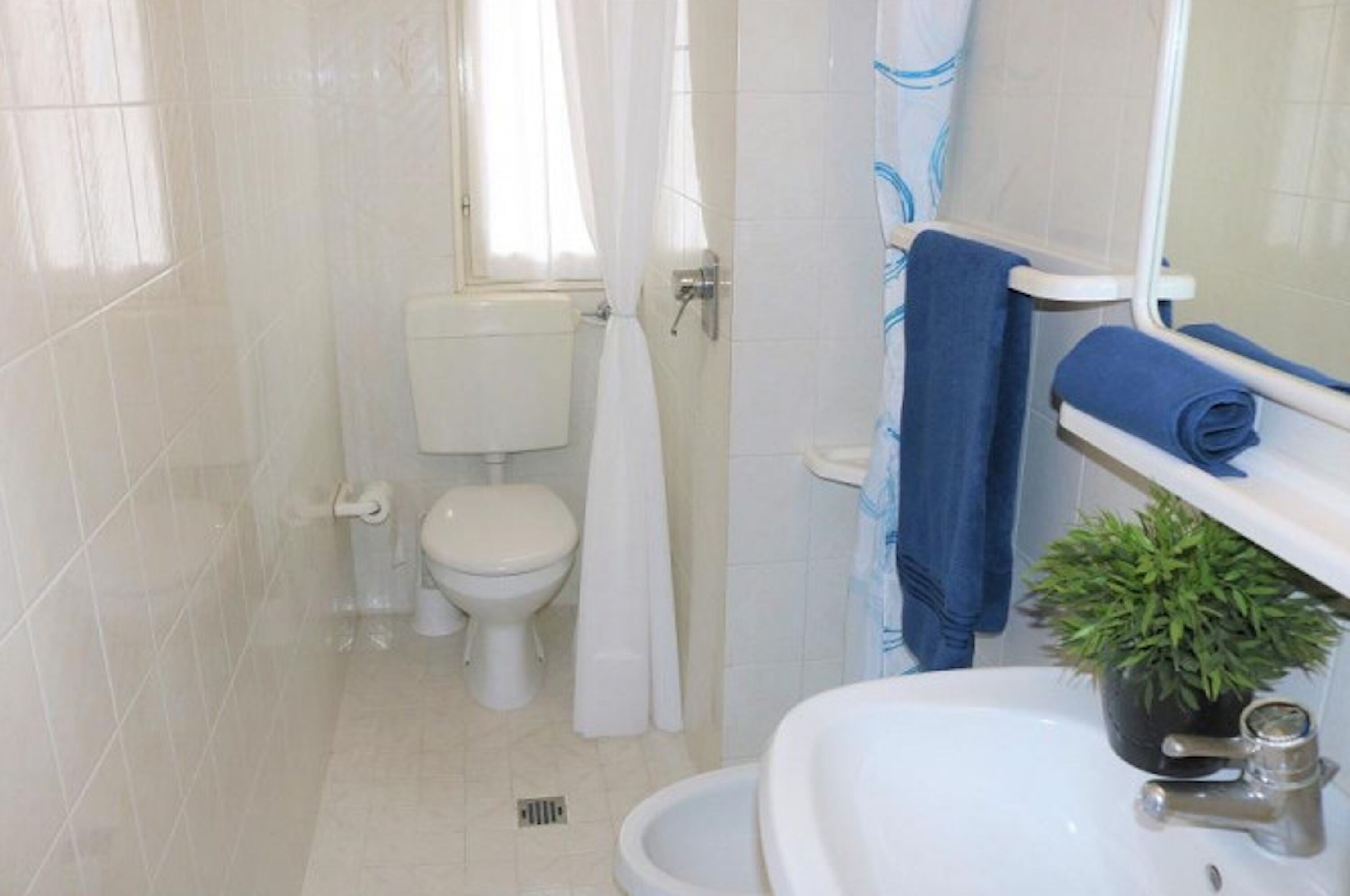 A bathroom with a toilet, sink, and shower area.