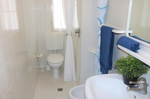 A bathroom with a toilet, sink, and shower area. - Modern Flat on the Shores of Bibione (San Michele al Tagliamento)