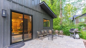 A modern house with a patio area featuring outdoor furniture and a grill. - Luxury Mountain-Modern Retreat 3BR near Glacier National Park & Whitefish (Columbia Falls)