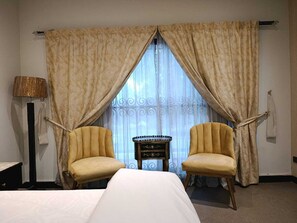 A hotel room with two chairs, a bed, a lamp, and a small table. - Spacious 6-bedroom house in DHA Phase 5 Lahore (Lahore)