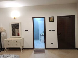 A hallway with a white console table, a dark wooden door, and a light switch on the wall.