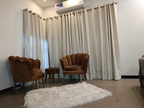 A living room with two brown armchairs, a white shag rug, and a white curtain backdrop.