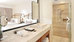 Une salle de bain moderne avec un grand miroir, deux lavabos, une douche et un meuble-lavabo en bois.
