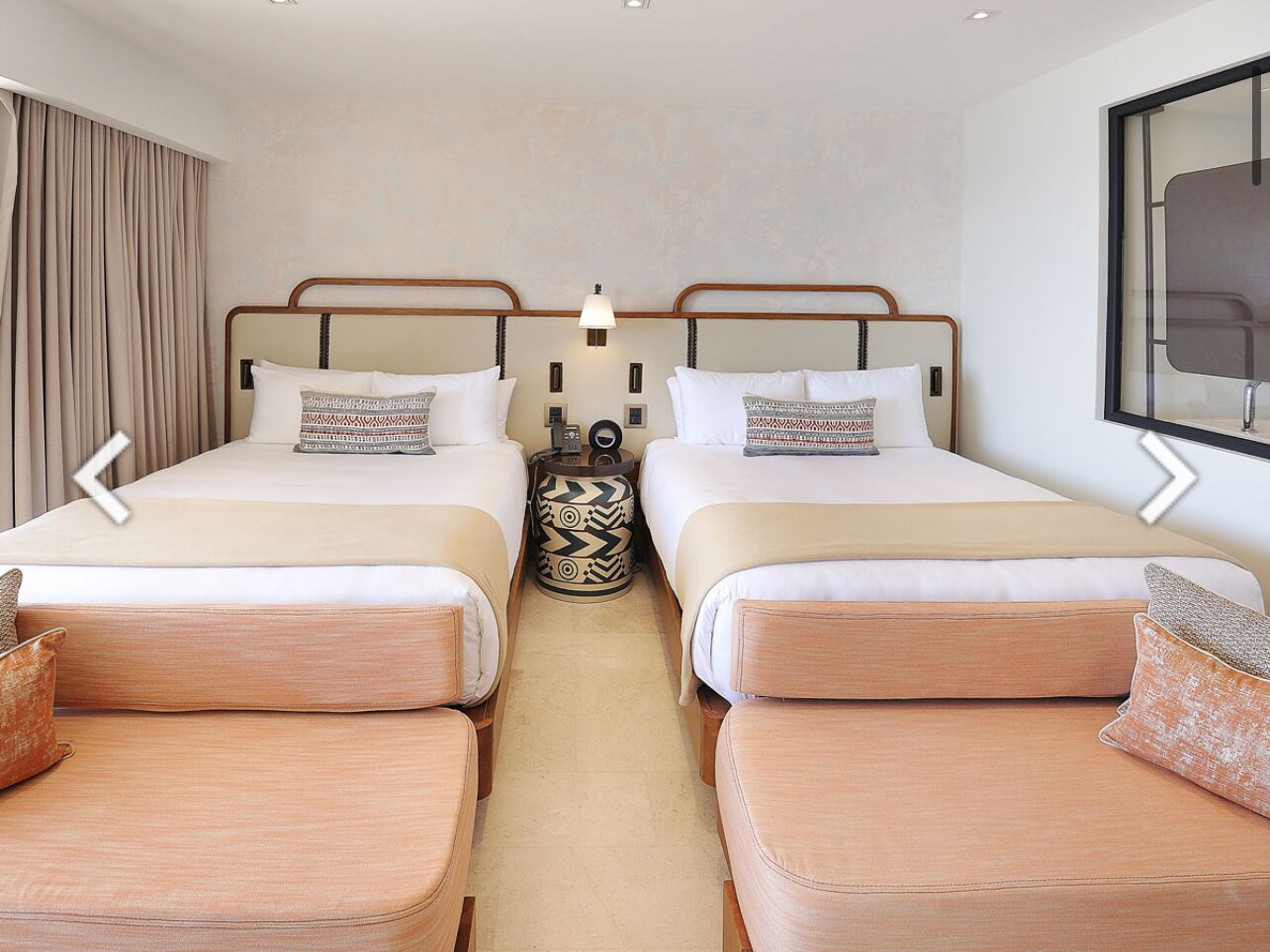 A hotel room with two beds, a small table, and a sofa.