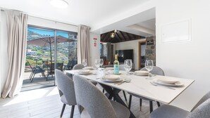 A dining area with a table set for four, a bottle of wine, and a view of the outdoors.