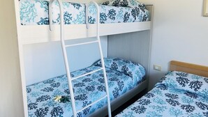 A bunk bed with a ladder, blue patterned bedding, and a wooden headboard. - Comfortable Flat a few Steps From the Beach (San Michele al Tagliamento)