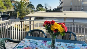 A balcony with a table set for two, featuring a floral tablecloth and a vase with flowers. - Comfortable Flat a few Steps From the Beach (San Michele al Tagliamento)