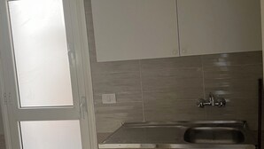 A kitchen with a stainless steel sink, white cabinets, and a window.