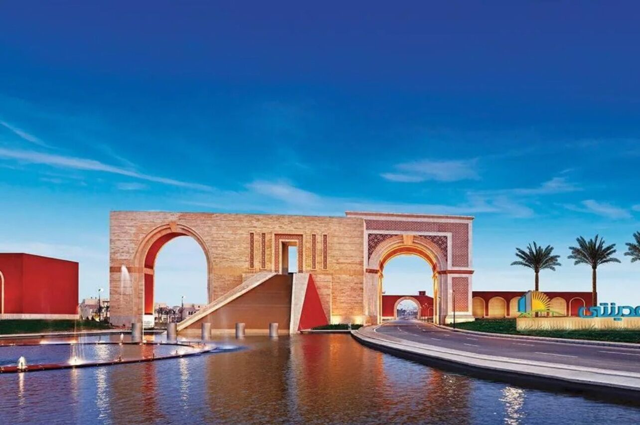 A large archway with a modern building in the background.