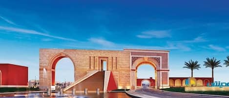 A large archway with a modern building in the background.