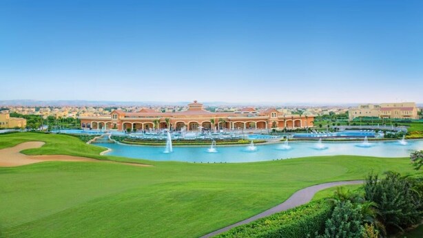 A large building with a central courtyard and multiple fountains, surrounded by well-maintained lawns and pathways.