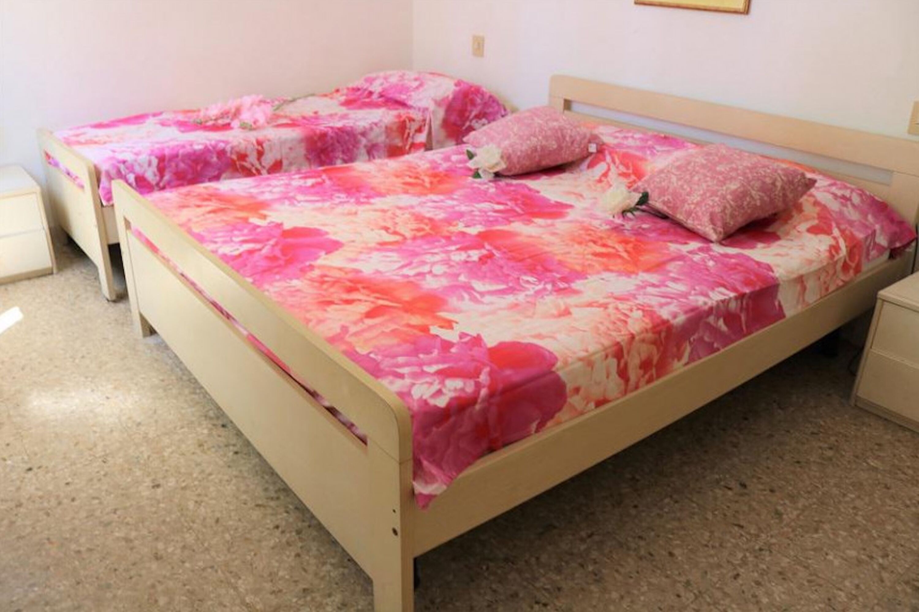A double bed with a floral bedspread, two bedside tables, and a nightstand.