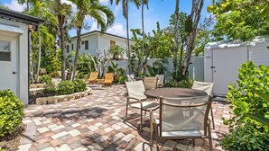 Une terrasse avec un sol en briques, des meubles d’extérieur et des palmiers.