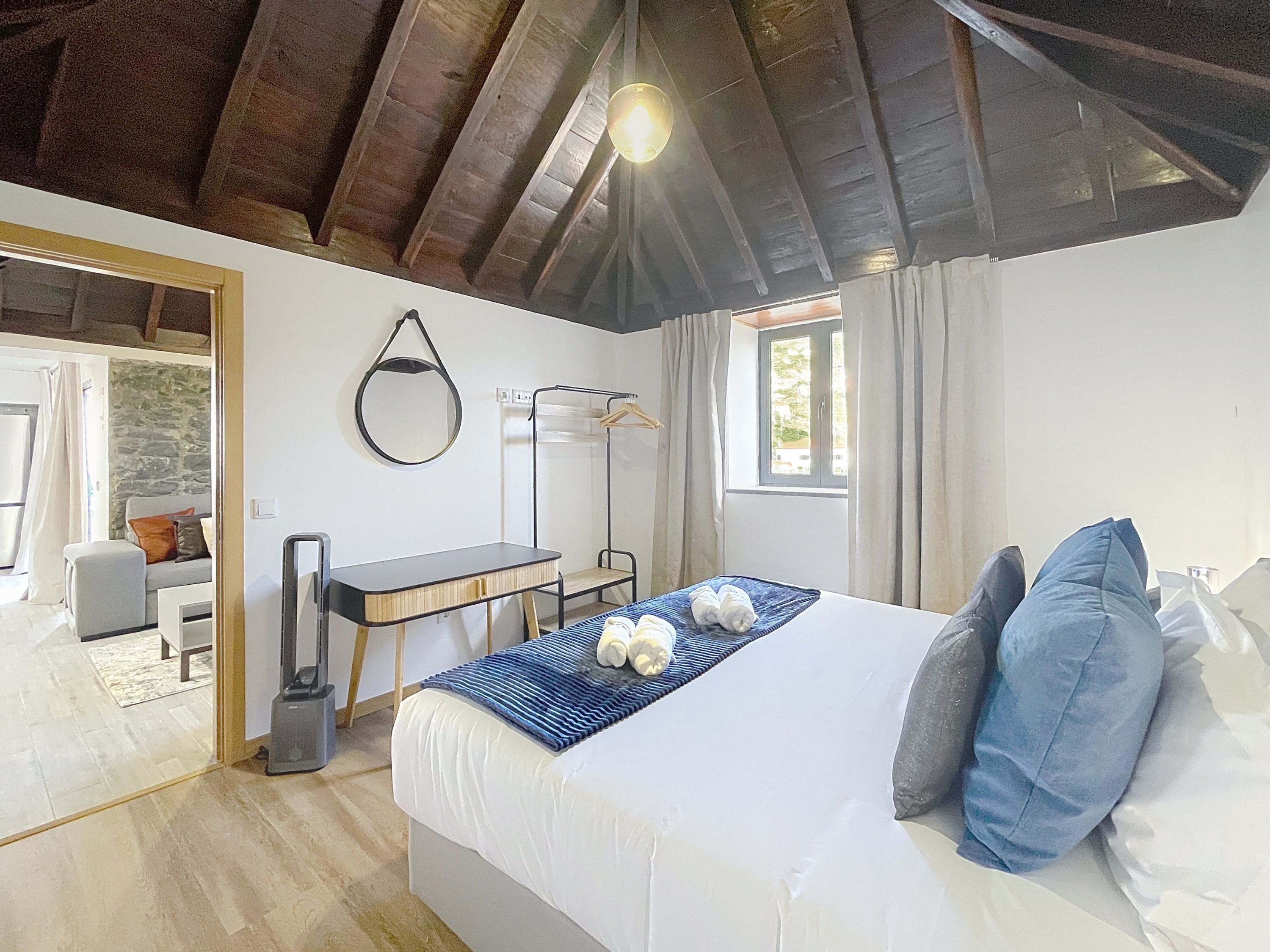 Ein Schlafzimmer mit Bett, Schreibtisch, Stuhl, Spiegel und Fenster.