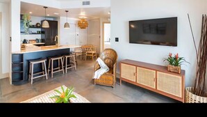 A modern living room with a large flat-screen TV mounted on the wall, a dining area with a table and chairs, and a kitchen area with a bar counter and stools. - Miami Penthouse, Rooftop, Free Parking (Miami)