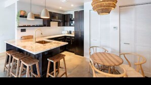 A modern kitchen with a central island, wooden stools, and a hanging light fixture. - Miami Penthouse, Rooftop, Free Parking (Miami)