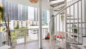 A spacious balcony with a view of high-rise buildings, a white railing, and a hanging light fixture. - Miami Penthouse, Rooftop, Free Parking (Miami)