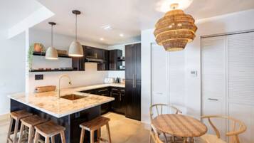 Une cuisine moderne avec un îlot central, des tabourets en bois et un luminaire suspendu.