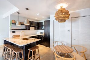 A modern kitchen with a central island, wooden stools, and a hanging light fixture. - Miami Penthouse, Rooftop, Free Parking (Miami)