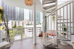 A spacious balcony with a view of high-rise buildings, a white railing, and a hanging light fixture. - Miami Penthouse, Rooftop, Free Parking (Miami)
