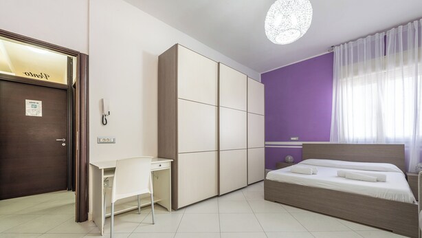 A bedroom with a bed, a desk, and a wardrobe. - Thanit rooms (Cagliari)
