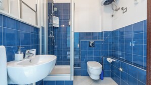 Un bagno moderno con un ampio lavandino bianco, una doccia vetrata e un water bianco.