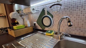 A modern kitchen with a stainless steel sink, a green cutting board, and a paper towel dispenser. - Vacation House "al Vicoletto" (Pratola Peligna)