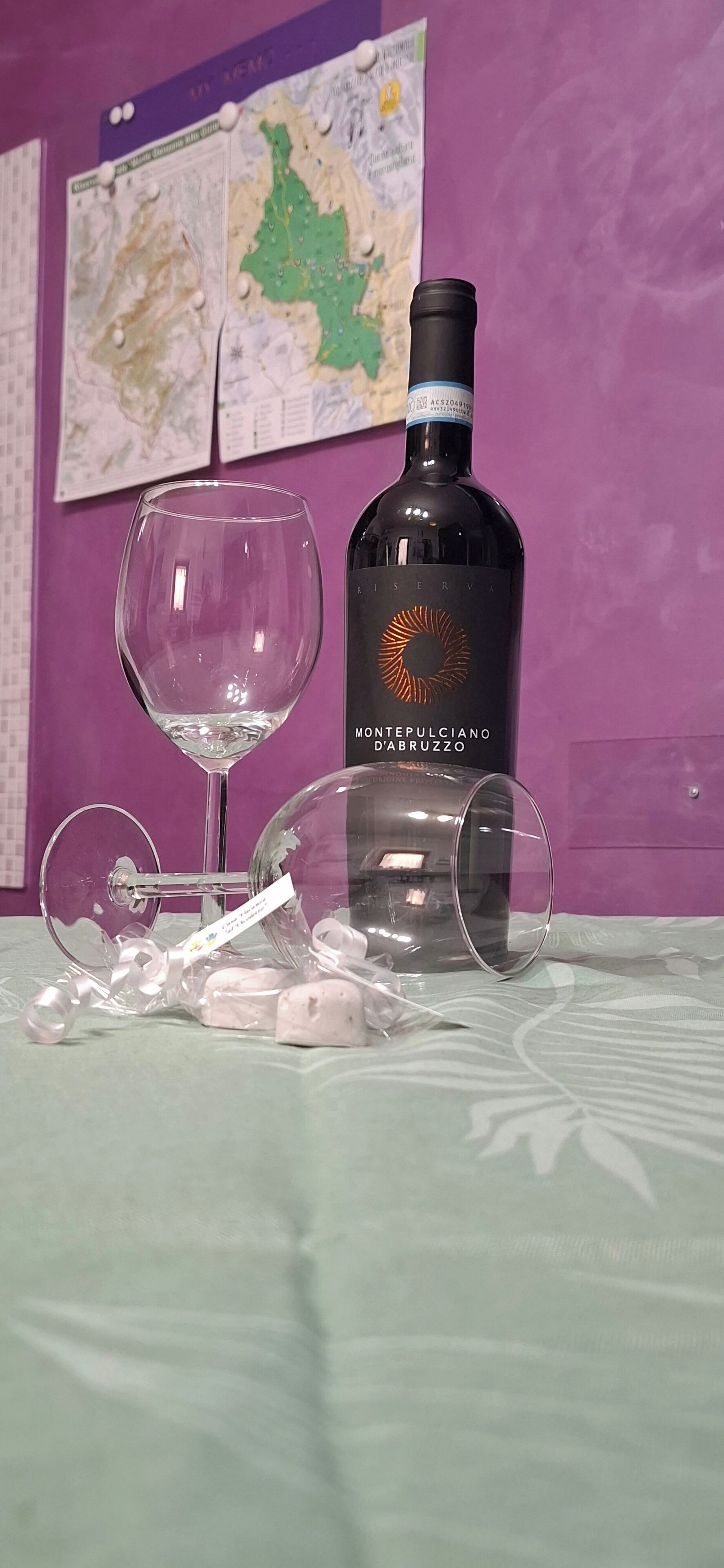 Eine Flasche Montrepulciano d'Abruzzo, ein Weinglas und eine Karaffe auf einem Tisch, im Hintergrund eine lilafarbene Wand.