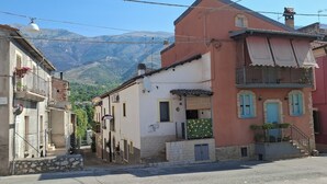 A narrow street with buildings, a car, and mountains in the background. - Vacation House "al Vicoletto" (Pratola Peligna)
