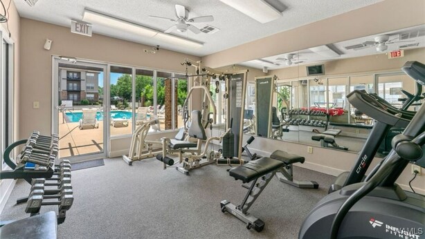 Une salle de sport équipée de matériel d’exercice, d’un tapis de course et d’une piscine visible à travers les portes vitrées.