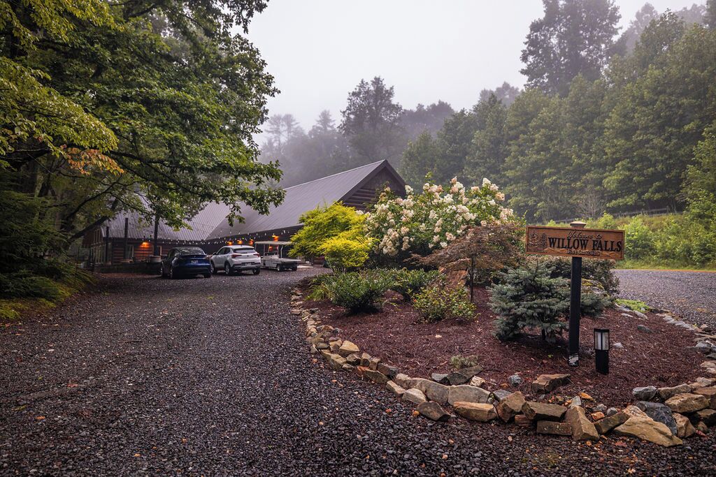L’entrée d’un chalet, avec une allée gravillonnée, une enseigne indiquant « Willow Falls », et un bâtiment doté d’un toit sombre.