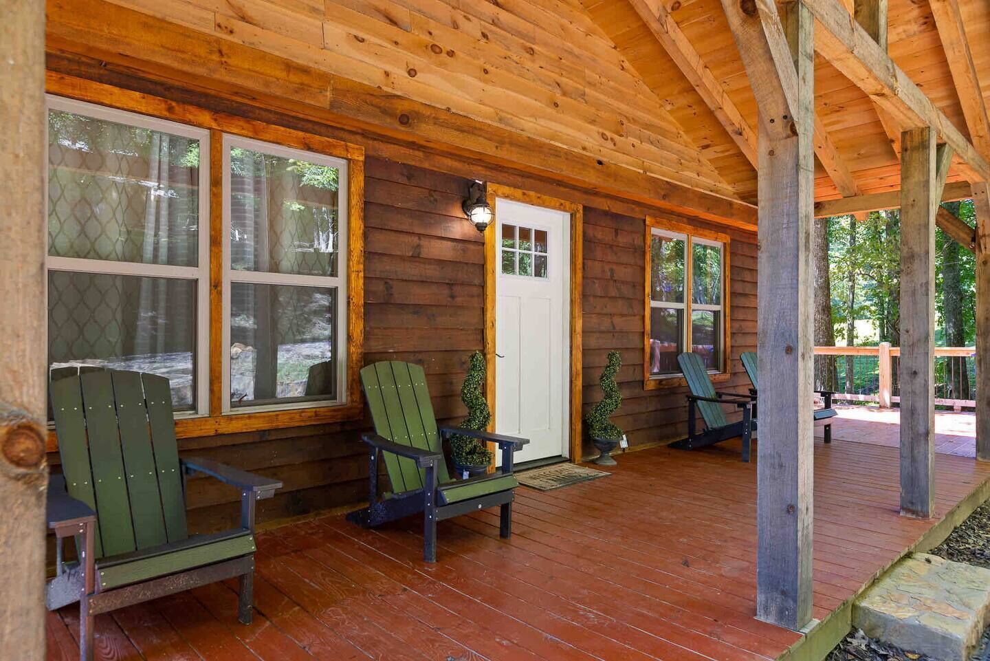 A wooden cabin with a porch, large windows, and outdoor seating.